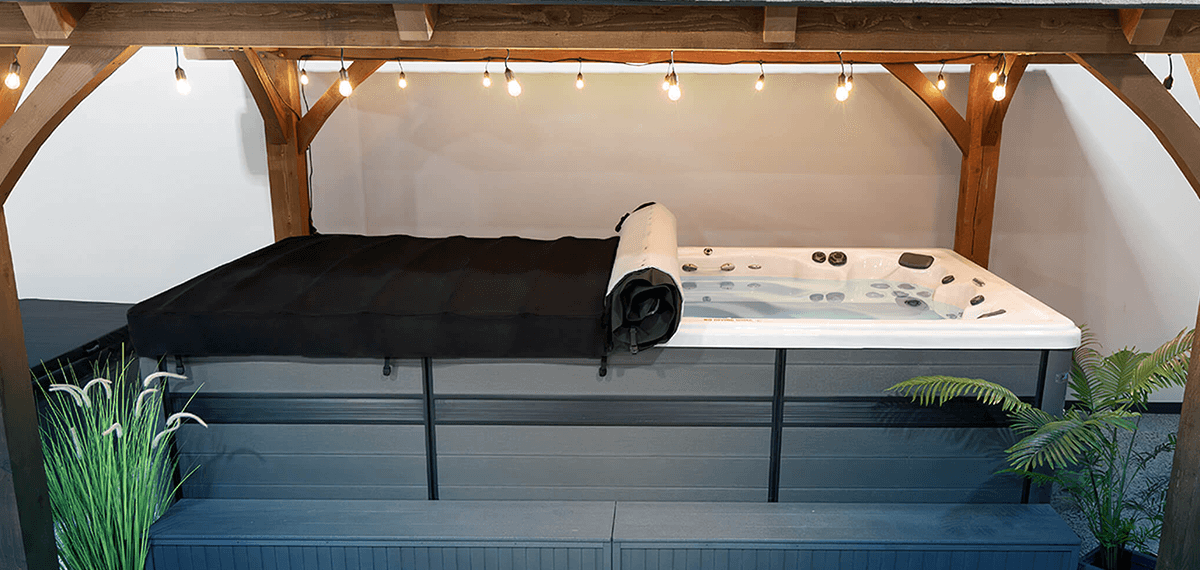 MasterSpas Swim Spa underneath an awning with lights and featuring the axis cover system rolled back to expose the water.