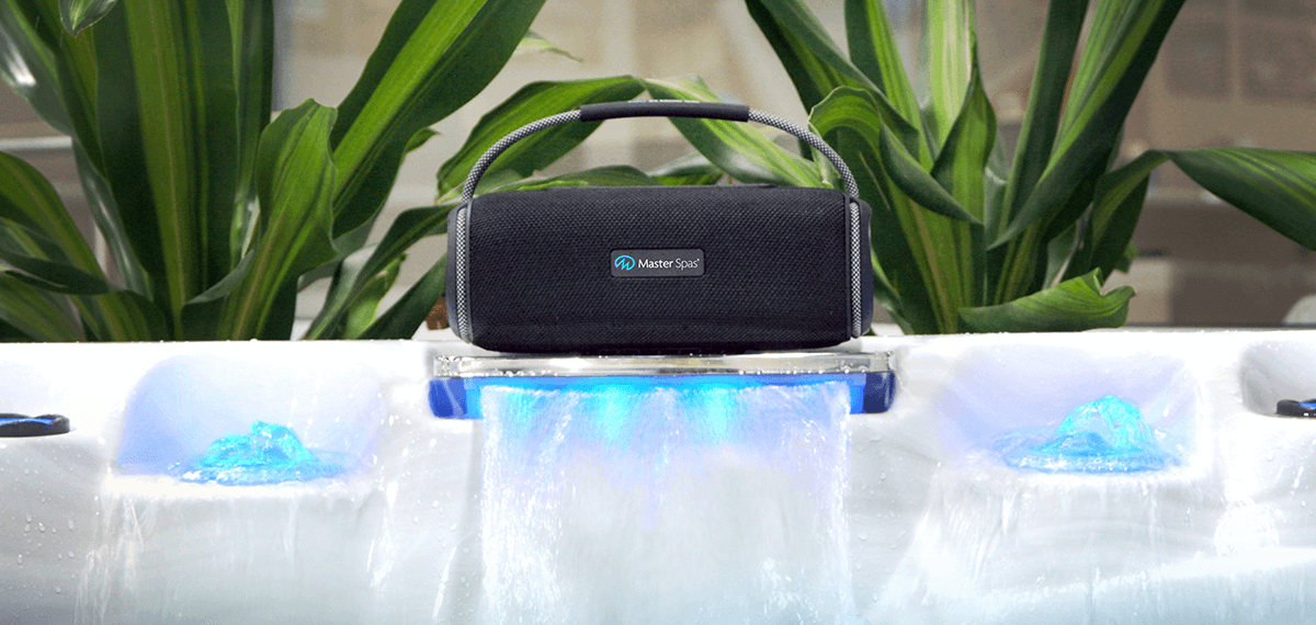 MasterSpas bluetooth speaker placed on top of the output of a waterfall feature on a hot tub.
