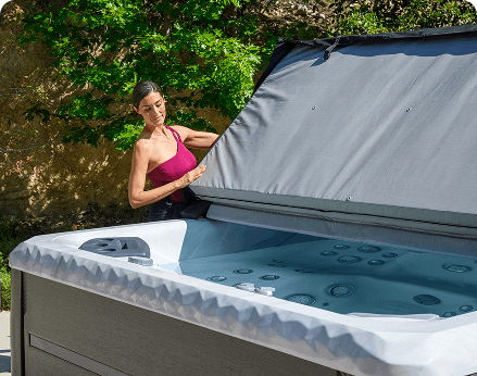 Woman lifting cover off of a hot tub.