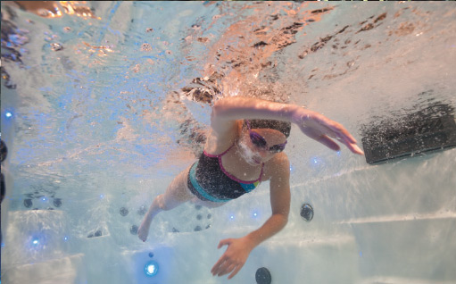 underwater view of a kid swimming in a swim spa